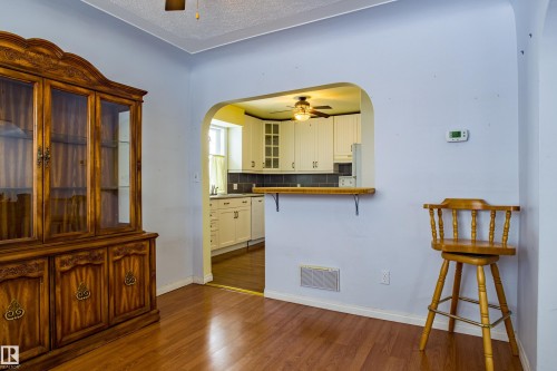 Kitchen with a breakfast bar area, a ceiling fan, glass insert cabinets, white cabinetry, and a textured ceiling - 9228 124A Avenue, Edmonton, AB - Indoor