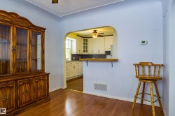 Kitchen with a breakfast bar area, a ceiling fan, glass insert cabinets, white cabinetry, and a textured ceiling - 