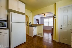 Kitchen featuring freestanding refrigerator, arched walkways, a ceiling fan, dark wood finished floors, and stainless steel microwave - 