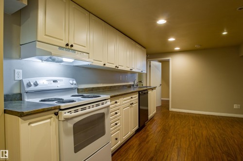 Kitchen featuring white range with electric cooktop, dark countertops, recessed lighting, under cabinet range hood, and dark wood-type flooring - 9228 124A Avenue, Edmonton, AB - Indoor Photo Showing Kitchen