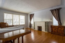 Bedroom with wood finished floors, a textured ceiling, and a tiled fireplace - 