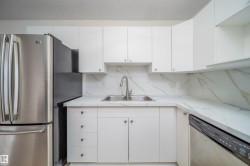 Kitchen with stainless steel appliances, white cabinetry, backsplash, a textured ceiling, and light stone countertops - 