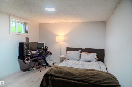 Bedroom with an office area, a textured ceiling, and wood finished floors - 12005 40 St, Edmonton, AB - Indoor Photo Showing Bedroom