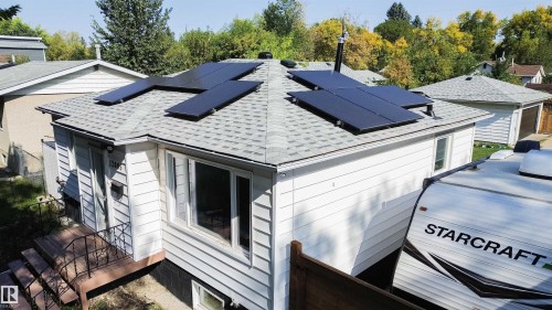 View of home's exterior featuring a wooden deck, solar panels, and a shingled roof - 12005 40 St, Edmonton, AB - Outdoor