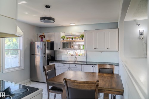 Kitchen featuring white cabinetry, light marble finish floors, freestanding refrigerator, and black electric range oven - 12005 40 St, Edmonton, AB - Indoor Photo Showing Kitchen With Double Sink