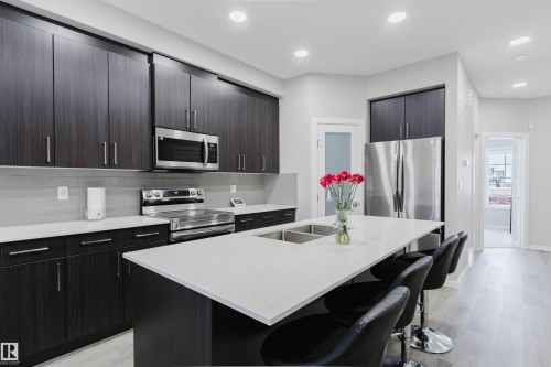 Kitchen with a kitchen bar, appliances with stainless steel finishes, modern cabinets, decorative backsplash, and light wood-type flooring - 343 Edgemont Drive, Edmonton, AB - Indoor Photo Showing Kitchen With Double Sink With Upgraded Kitchen