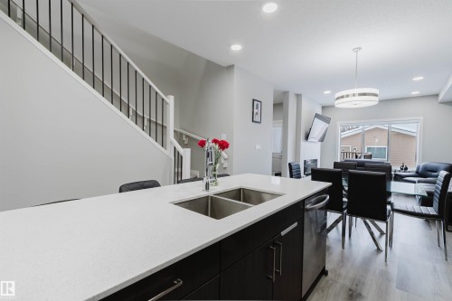 Kitchen featuring dark cabinetry, hanging light fixtures, light stone counters, recessed lighting, and dishwasher - 343 Edgemont Drive, Edmonton, AB - Indoor Photo Showing Kitchen With Double Sink