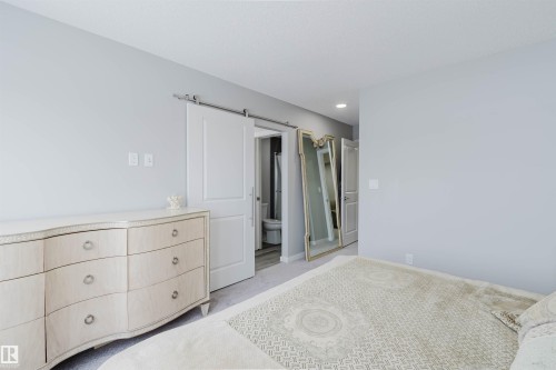 Bedroom featuring a barn door, ensuite bathroom, and light carpet - 343 Edgemont Drive, Edmonton, AB - Indoor Photo Showing Bedroom