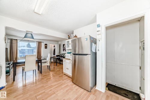 Kitchen with freestanding refrigerator, a textured ceiling, white cabinetry, light wood-style floors, and glass insert cabinets - 15515 92A Avenue, Edmonton, AB - Indoor