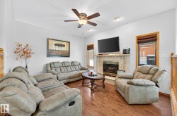 Living room with wood finished floors, a high end fireplace, and ceiling fan - 