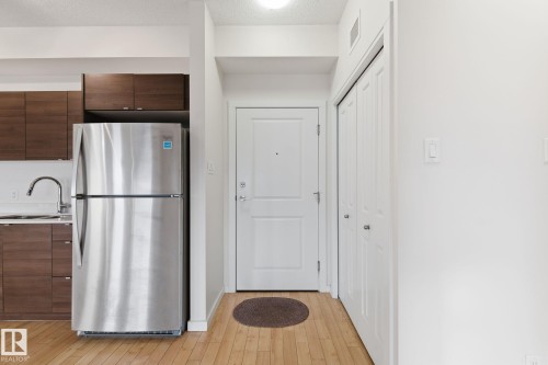 Kitchen with freestanding refrigerator, dark brown cabinets, modern cabinets, light countertops, and light wood-style flooring - 405 9517 160 Avenue, Edmonton, AB - Indoor