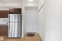 Kitchen with freestanding refrigerator, dark brown cabinets, modern cabinets, light countertops, and light wood-style flooring - 