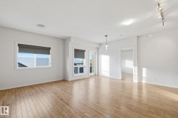Unfurnished living room featuring rail lighting, light wood finished floors, and a textured ceiling - 