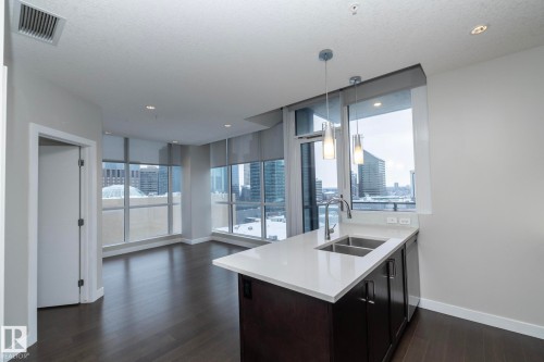 Kitchen with hanging light fixtures, dark wood-style floors, light stone countertops, a city view, and open floor plan - 1201 10238 103 Street, Edmonton, AB - Indoor Photo Showing Kitchen With Double Sink