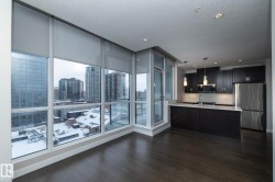 Kitchen featuring stainless steel appliances, a peninsula, a wall of windows, dark wood-type flooring, and hanging light fixtures - 