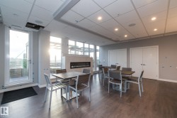 Dining room featuring a paneled ceiling, a glass covered fireplace, dark wood-type flooring, and a wall of windows - 
