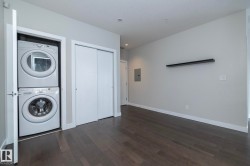 Laundry area with dark wood finished floors, stacked washer and clothes dryer, and electric panel - 