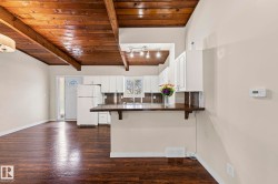 Kitchen with dark countertops, a wood ceiling with exposed beams, a breakfast bar, freestanding refrigerator, and dark wood finished floors - 