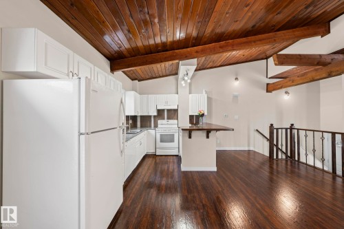 Kitchen with white appliances, a breakfast bar area, white cabinetry, wood ceiling, and dark wood finished floors - 15 Northwoods Village, Edmonton, AB - Indoor Photo Showing Kitchen