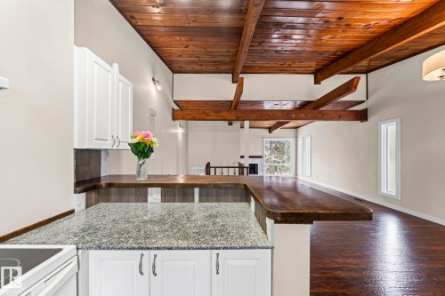 Kitchen with a wooden ceiling with exposed beams, white cabinets, open floor plan, a kitchen bar, and a peninsula - 15 Northwoods Village, Edmonton, AB - Indoor Photo Showing Kitchen