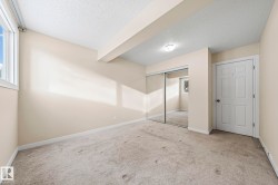 Unfurnished bedroom with a textured ceiling, light colored carpet, a closet, and beamed ceiling - 
