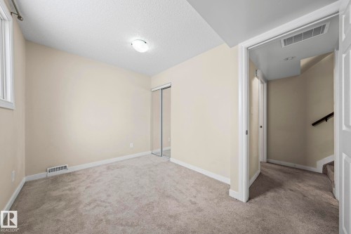 Unfurnished bedroom featuring a textured ceiling, carpet, and a closet - 15 Northwoods Village, Edmonton, AB - Indoor Photo Showing Other Room