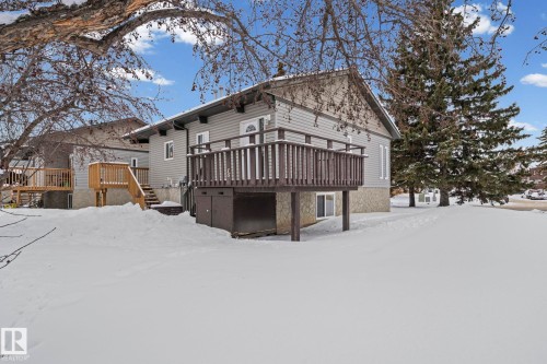 View of snow covered exterior featuring a deck and stone siding - 15 Northwoods Village, Edmonton, AB - Outdoor With Deck Patio Veranda