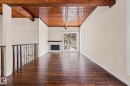 Unfurnished living room featuring wood ceiling, hardwood / wood-style floors, and a fireplace - 15 Northwoods Village, Edmonton, AB  - Indoor Photo Showing Other Room With Fireplace 