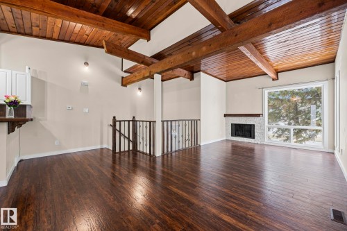 Unfurnished living room featuring wooden ceiling, dark wood-style floors, and a fireplace - 15 Northwoods Village, Edmonton, AB - Indoor With Fireplace