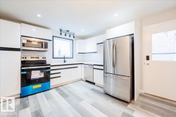 Kitchen with white cabinets, stainless steel appliances, modern cabinets, and light wood finished floors - 