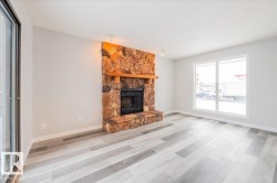 Unfurnished living room featuring a stone fireplace and wood finished floors - 