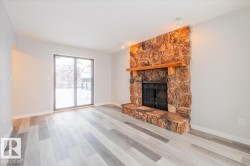 Unfurnished living room with light wood-type flooring and a stone fireplace - 