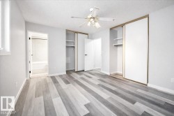 Unfurnished bedroom featuring a textured ceiling, multiple closets, light wood-style flooring, a ceiling fan, and ensuite bathroom - 