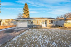 Ranch-style house with concrete driveway, a garage, stone siding, and french doors - 