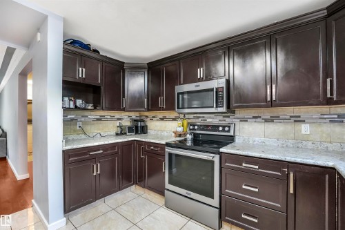 Kitchen with appliances with stainless steel finishes, dark brown cabinets, light tile patterned flooring, backsplash, and open shelves - 13335 106 Street, Edmonton, AB - Indoor Photo Showing Kitchen