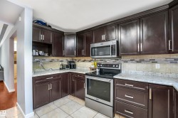 Kitchen with appliances with stainless steel finishes, dark brown cabinets, light tile patterned flooring, backsplash, and open shelves - 