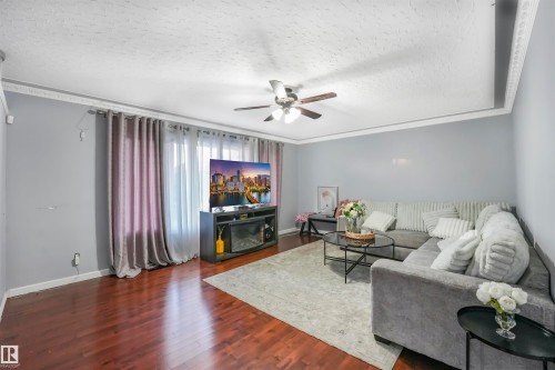Living room featuring a textured ceiling, dark wood-style flooring, a ceiling fan, and crown molding - 13335 106 Street, Edmonton, AB - Indoor Photo Showing Living Room