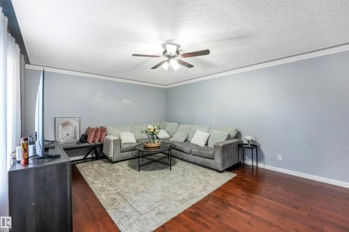 Living room with dark wood-style floors, ceiling fan, a textured ceiling, and ornamental molding - 13335 106 Street, Edmonton, AB - Indoor Photo Showing Living Room