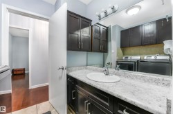 Half bathroom with washing machine and dryer, vanity, light wood finished floors, and decorative backsplash - 