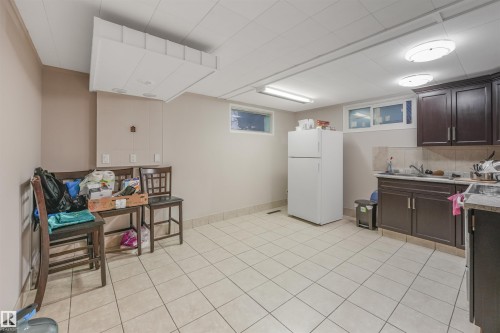 Kitchen with dark brown cabinets, freestanding refrigerator, tasteful backsplash, and light countertops - 13335 106 Street, Edmonton, AB - Indoor