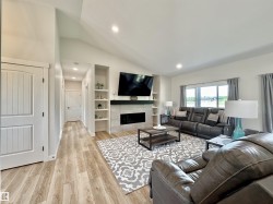 Living room featuring lofted ceiling, built in shelves, recessed lighting, light wood finished floors, and a tile fireplace - 