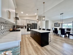 Kitchen featuring white cabinets, hanging light fixtures, a kitchen bar, lofted ceiling, and light stone counters - 
