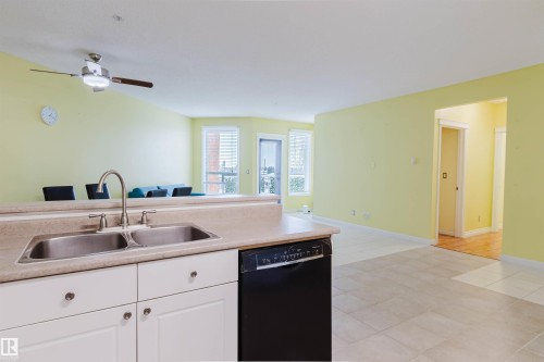 Kitchen featuring dishwasher, white cabinetry, light countertops, open floor plan, and a ceiling fan - 406 9120 156 Street, Edmonton, AB - Indoor Photo Showing Kitchen With Double Sink