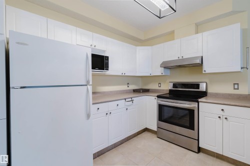 Kitchen featuring freestanding refrigerator, stainless steel electric range oven, white cabinets, and light countertops - 406 9120 156 Street, Edmonton, AB - Indoor Photo Showing Kitchen