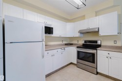 Kitchen featuring freestanding refrigerator, stainless steel electric range oven, white cabinets, and light countertops - 