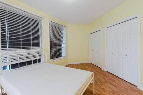 Bedroom with multiple closets, light wood-type flooring, and a textured ceiling - 406 9120 156 Street, Edmonton, AB - Indoor Photo Showing Bedroom