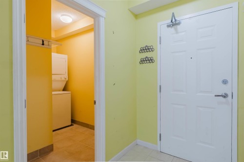 Laundry room with stacked washer and clothes dryer and light tile patterned floors - 406 9120 156 Street, Edmonton, AB - Indoor Photo Showing Laundry Room