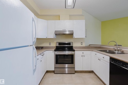 Kitchen with freestanding refrigerator, stainless steel electric range oven, dishwasher, and white cabinets - 406 9120 156 Street, Edmonton, AB - Indoor Photo Showing Kitchen With Double Sink