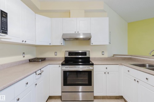 Kitchen featuring electric stove, white cabinets, under cabinet range hood, and light countertops - 406 9120 156 Street, Edmonton, AB - Indoor Photo Showing Kitchen