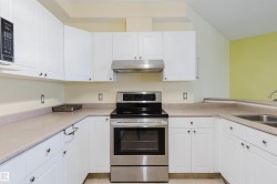 Kitchen featuring electric stove, white cabinets, under cabinet range hood, and light countertops - 